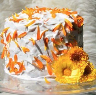 Edible petals on a celebration cake with white butter cream and orange calendula petals.