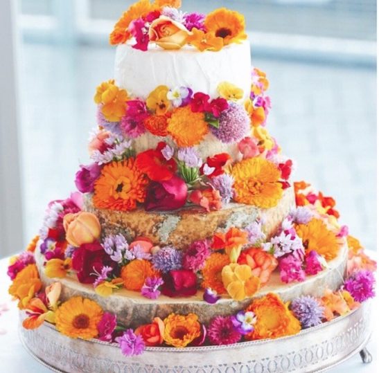 A wedding cake decorated with pink and orange flowers from The Edible Flower Garden.